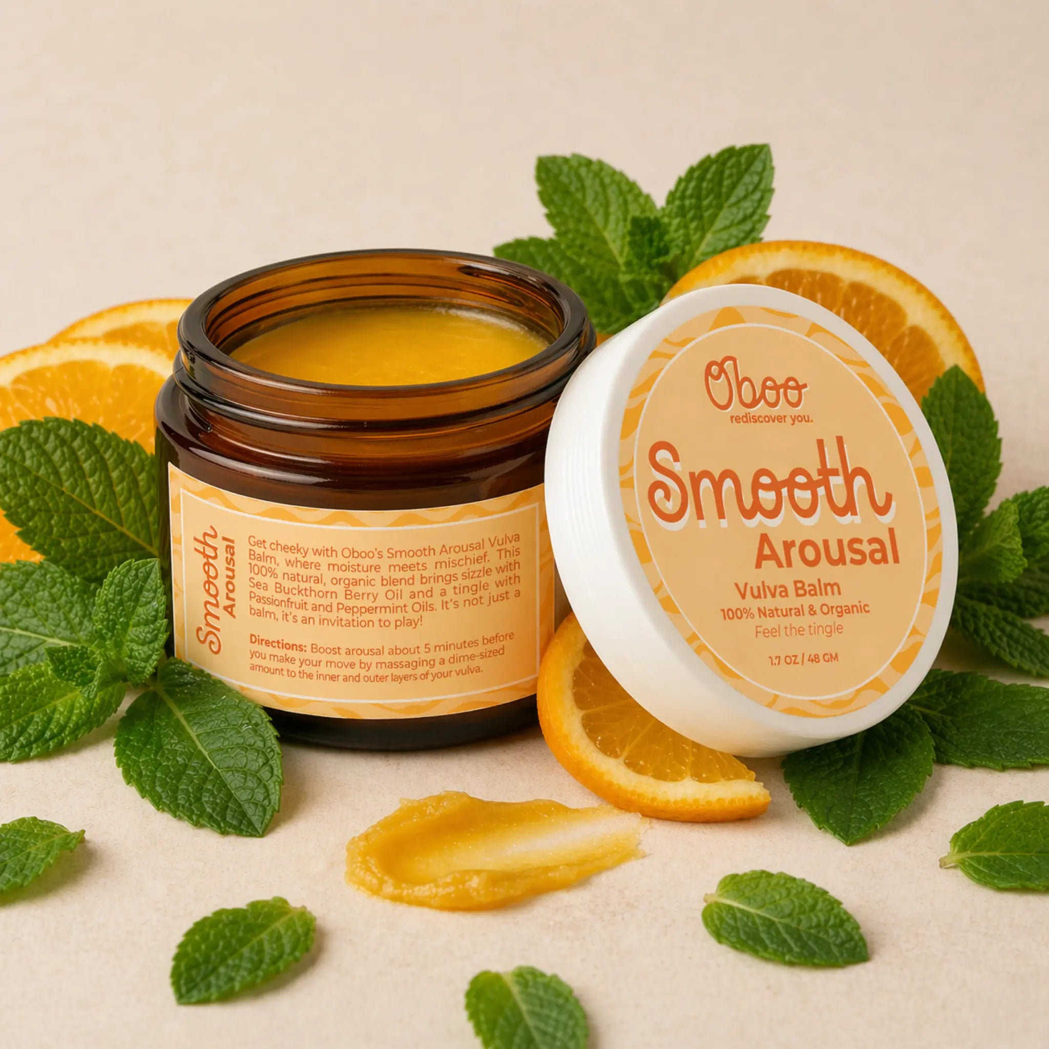 Open jar of Smooth Arousal Vulva Balm surrounded by fresh peppermint leaves and sliced sweet oranges — natural arousal balm for midlife