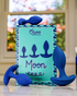 A blue anal training kit with four differently sized plugs is displayed next to the Oboo Moon product box on a reflective surface.