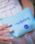 A woman in a white dress holds a light blue pouch with the words “hooked on a feeling” and the Oboo logo.