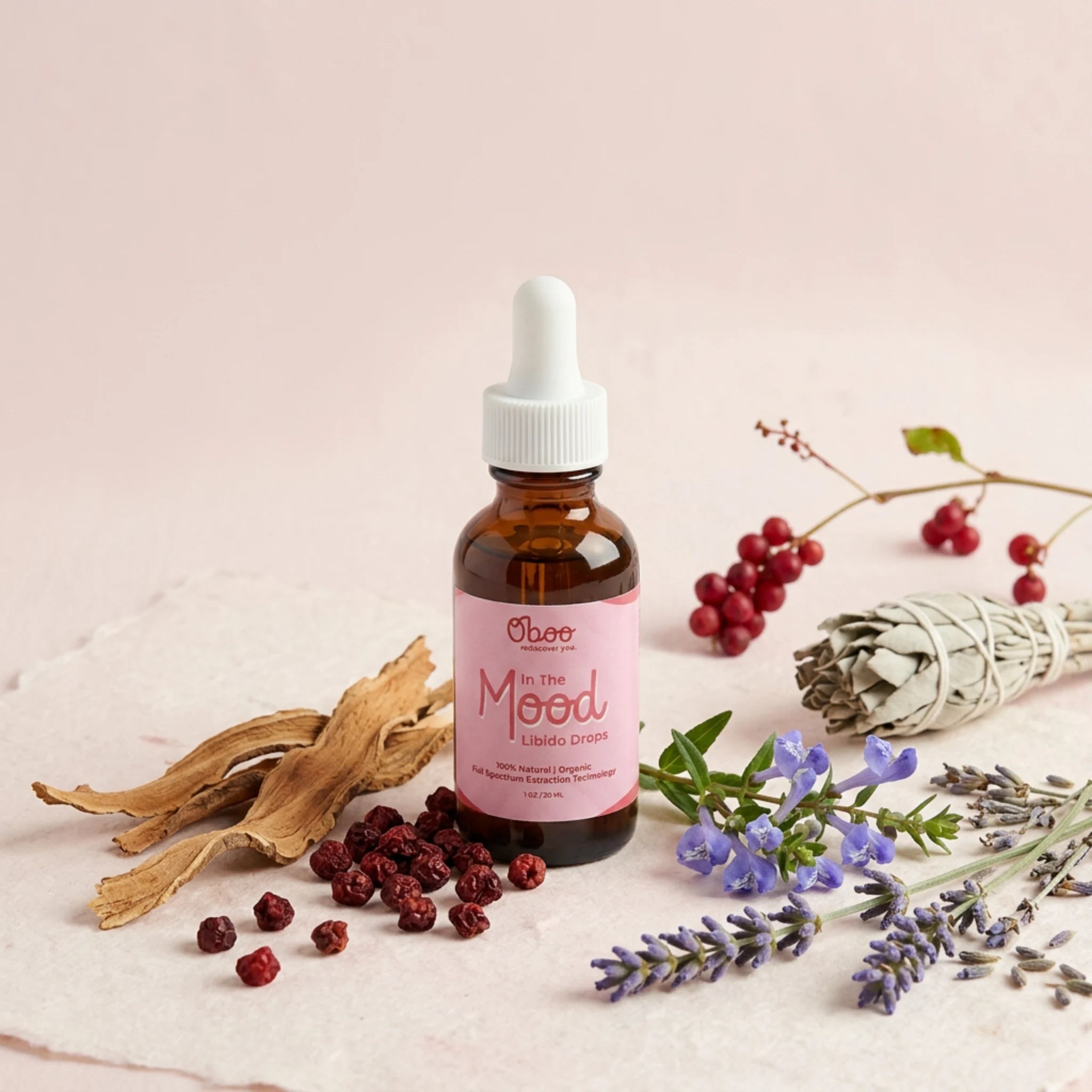 In the Mood Drops surrounded by white sage bundle, dried red schisandra berries, lavender, and herbal botanicals on a soft pink linen