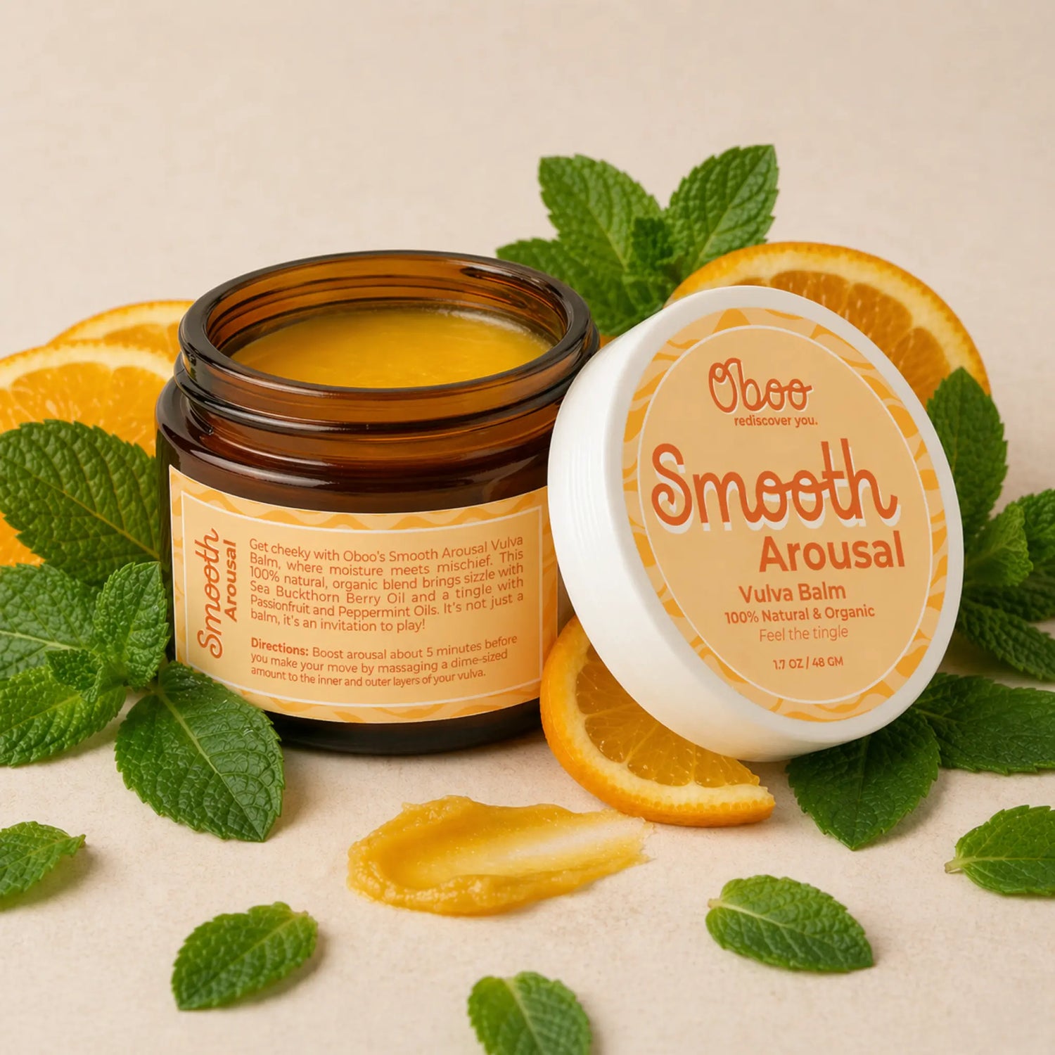 Open jar of Smooth Arousal Vulva Balm surrounded by fresh peppermint leaves and sliced sweet oranges — natural arousal balm for midlife