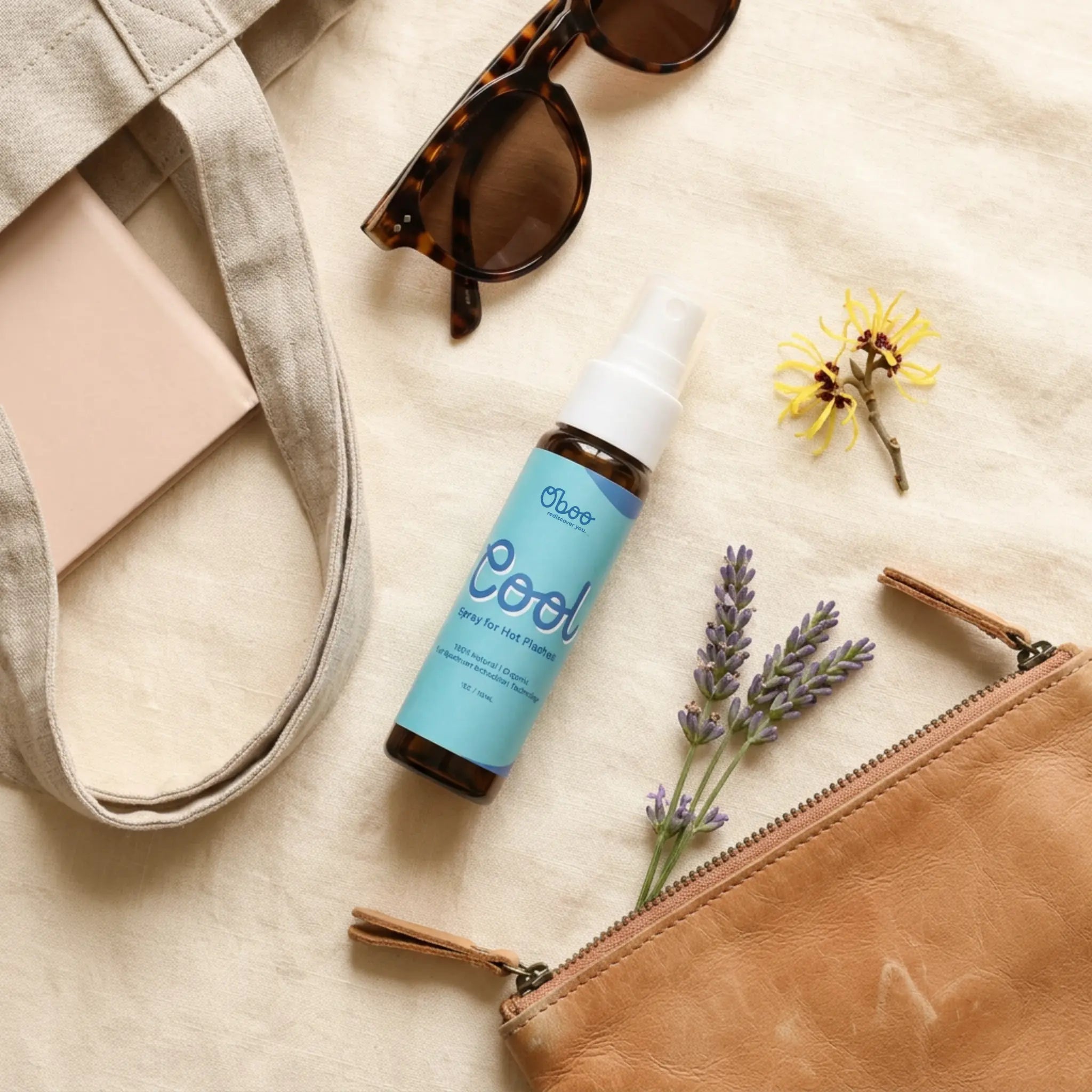 Flat lay with Oboo Cool Spray, tortoiseshell sunglasses, a tan zippered pouch, lavender, and witch hazel — purse-sized hot flash relief on the go