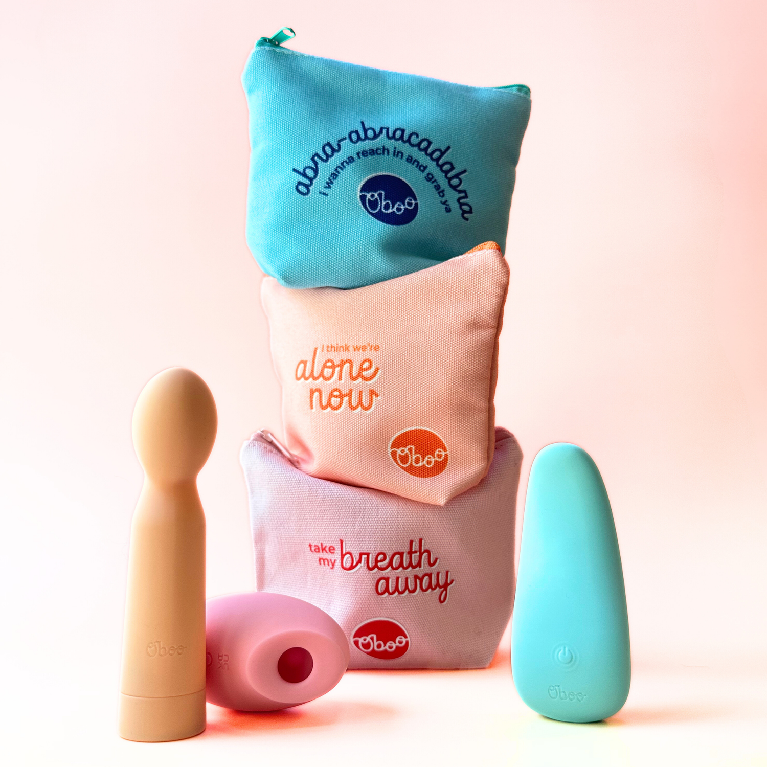Three colorful Oboo pouches, each holding a different massager, feature playful phrases like “abra-abracadabra” and “take my breath away.”