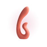 A coral-colored dual-stimulation massager with a curved, ergonomic design is displayed upright against a soft pink gradient background.