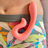 A coral-colored dual-stimulation massager rests on a person&