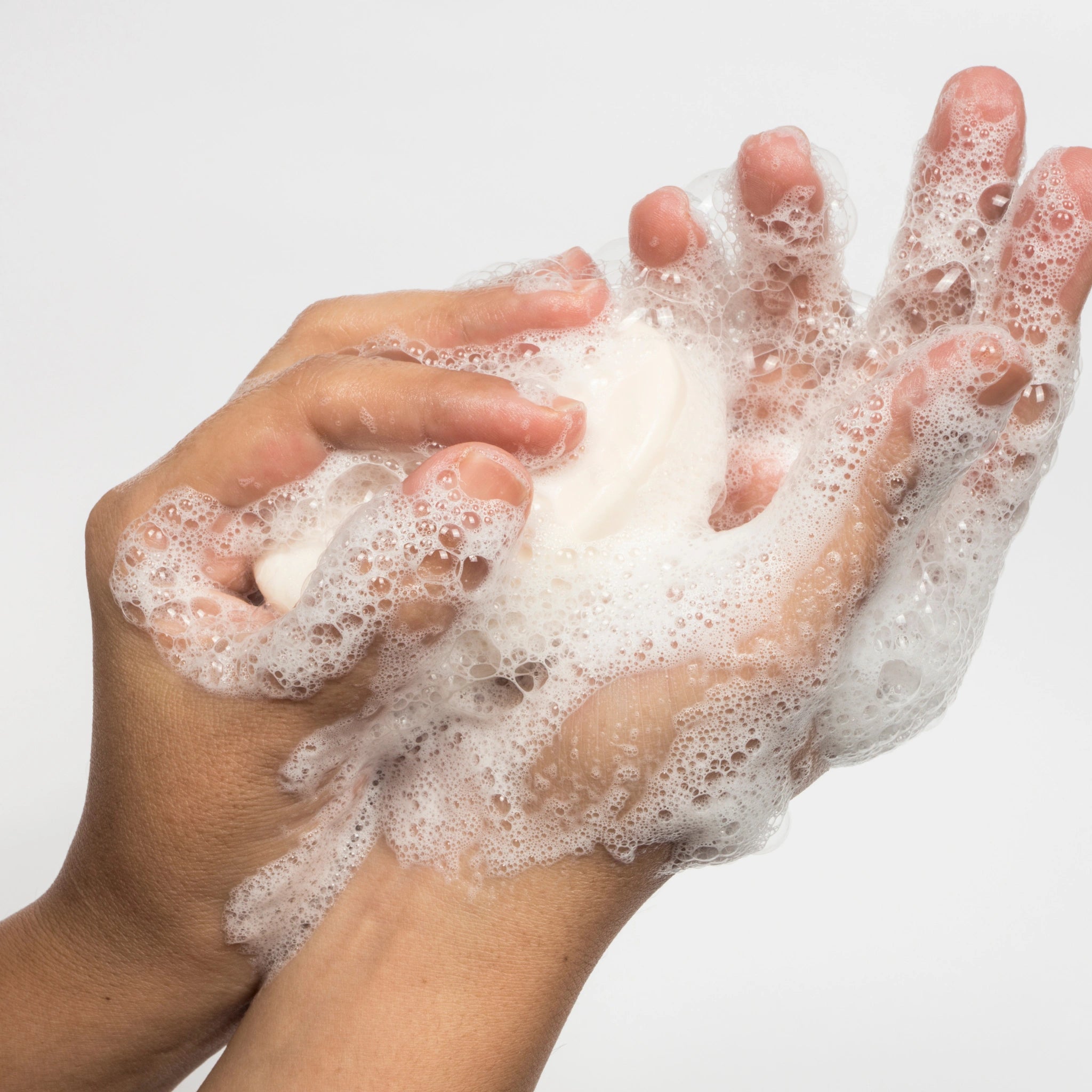 Close-up of two hands lathered with foam and holding a bar of soap, highlighting cleanliness, hygiene, and gentle cleansing.