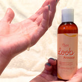 Hand squeezing clear gel from Oboo Loob Arousal bottle onto palm, demonstrating product texture and application.