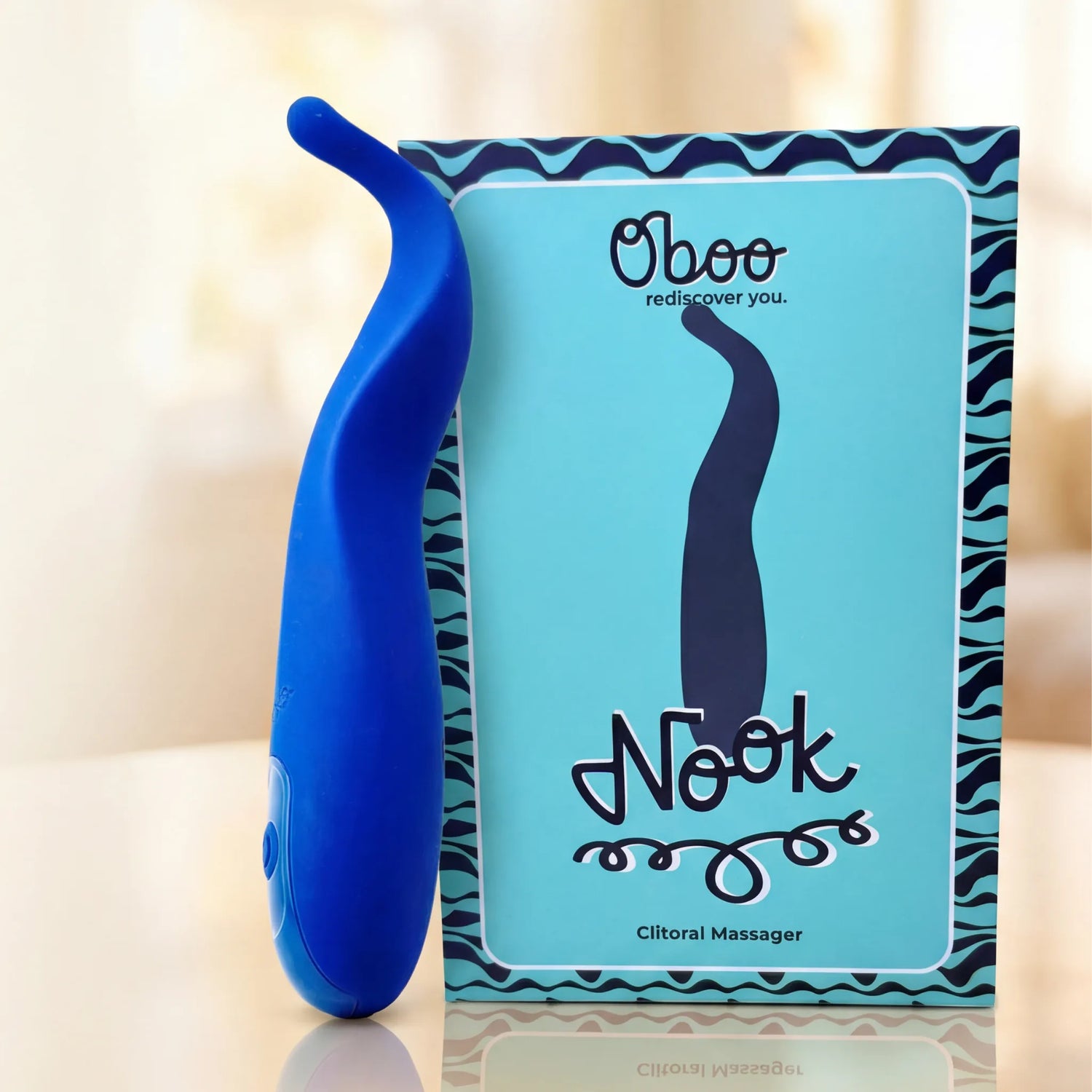 Blue Nook Clitoral Massager beside its teal Oboo product box with squiggle pattern — small, smart, and made for midlife couples