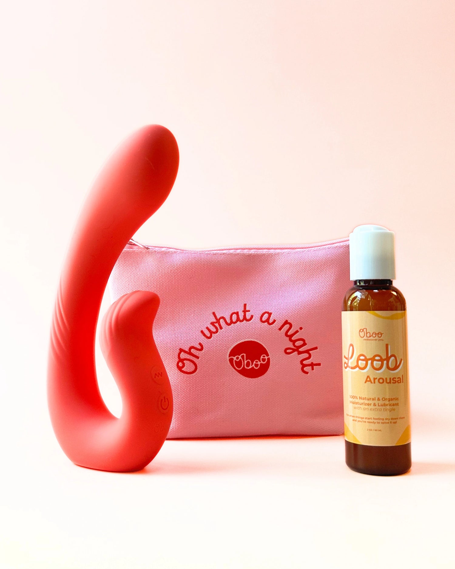 A red dual-action massager, pink “Oh what a night” pouch, and Oboo Loob Arousal bottle displayed against a peach background.